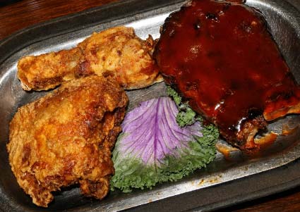 A Minnesota restaurant special: two fried chicken pieces, sauced rib, and leafy garnish on a tray.