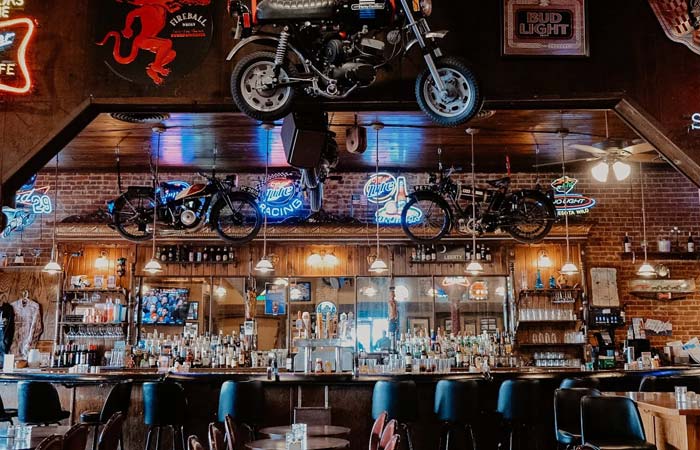 Bar interior at Libertys in Minnesota with neon signs, motorcycles, and bottles behind the counter.