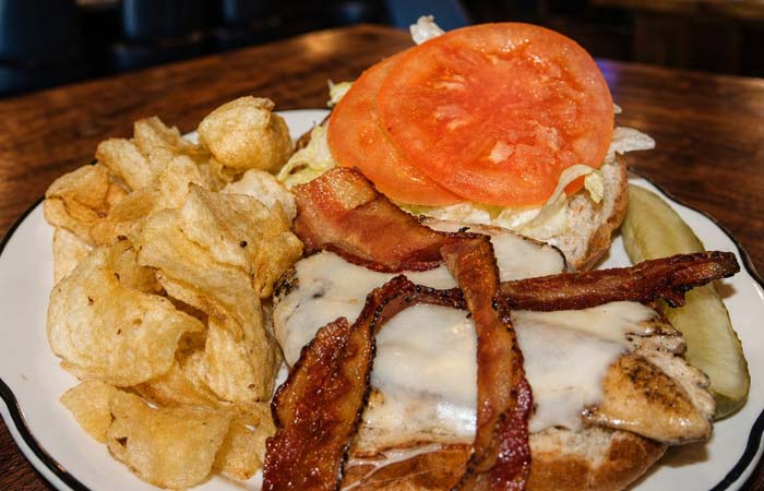 Chicken sandwich with bacon, cheese, and chips—classic fare at our Red Wing MN restaurant bar.