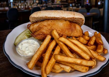 Fish sandwich with tartar sauce, fries, and a pickle served at a downtown Red Wing MN restaurant.
