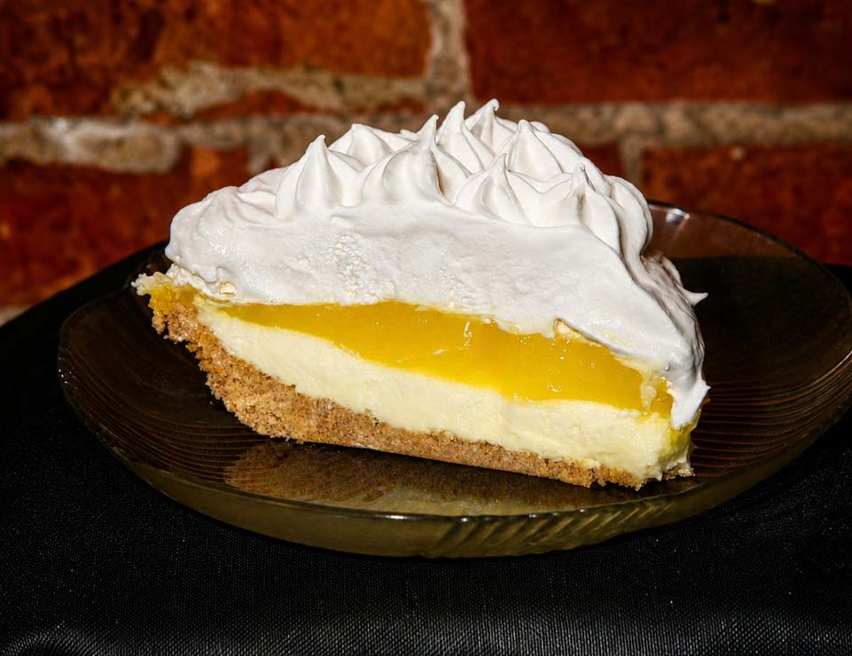 Slice of lemon pie with whipped topping at Liberty’s Bar, brick wall in background, Minnesota.